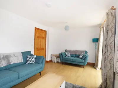 a living room with two blue couches and a table at Jacks Mews in Tintagel