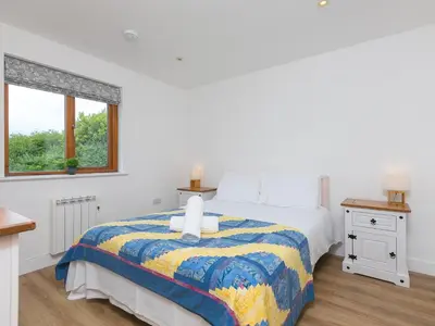 a white bedroom with a bed and a window at Tressa, Tor Down Quarry in Bodmin