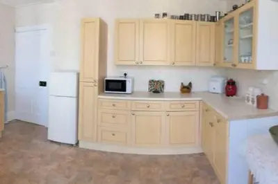 a kitchen with wooden cabinets and a white refrigerator at Millbrook in Helston