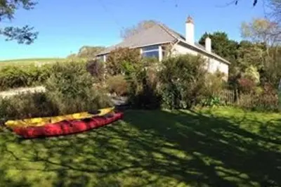 a house with a red and yellow object in the yard at Millbrook in Helston