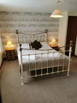 a bedroom with a white bed with a wooden wall at The Cornishman Inn in Tintagel