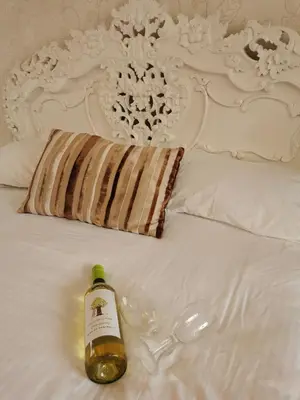 a bottle of wine sitting on top of a bed at The Cornishman Inn in Tintagel