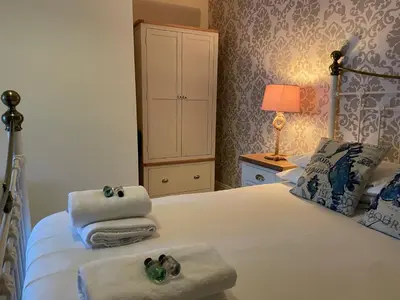 a bedroom with a bed with towels and a cabinet at The Cornishman Inn in Tintagel