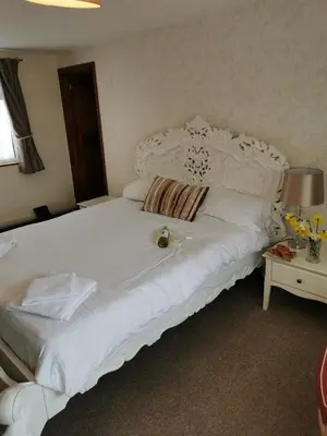 a large white bed in a room with a table at The Cornishman Inn in Tintagel