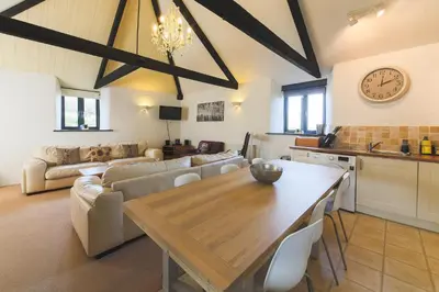 a kitchen and a living room with a table and a couch at Goonwinnow Farm Cottages in Newquay
