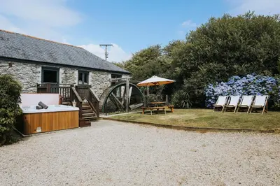 a house with a garden with chairs and an umbrella at Goonwinnow Farm Cottages in Newquay