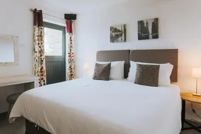 a bedroom with a large white bed and a window at Wheel House @ Goonwinnow Farm in Newquay