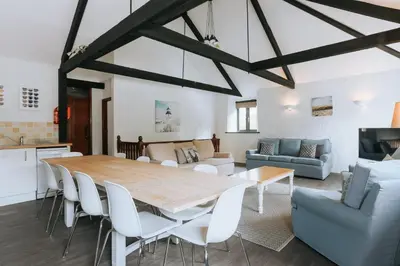 a kitchen and living room with a wooden table and chairs at Wheel House @ Goonwinnow Farm in Newquay