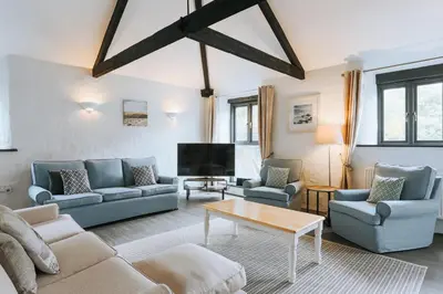 a living room with blue couches and a tv at Wheel House @ Goonwinnow Farm in Newquay
