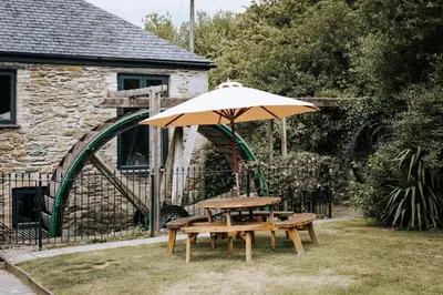 a picnic table and an umbrella in a yard at Wheel House @ Goonwinnow Farm in Newquay