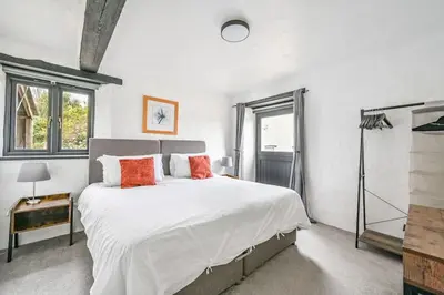 a bedroom with a large bed with white sheets and orange pillows at Mill House @ Goonwinnow Farm in Newquay
