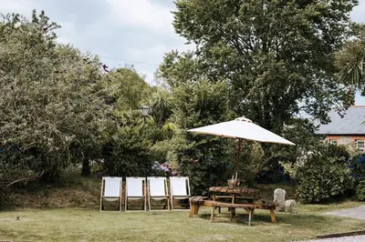 a picnic table and an umbrella in the grass at Mill House @ Goonwinnow Farm in Newquay