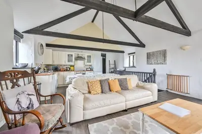 a living room with a white couch and a kitchen at Mill House @ Goonwinnow Farm in Newquay