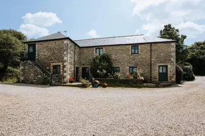 an old stone house with a gravel driveway at Mill House @ Goonwinnow Farm in Newquay