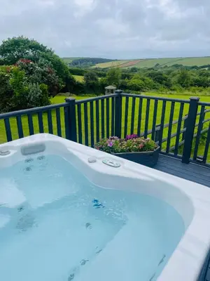 a jacuzzi tub on a deck with a garden at The Piggery @ Goonwinnow Farm in Newquay
