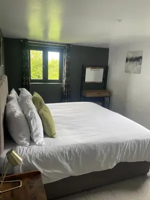 a bedroom with a large bed with white sheets and pillows at The Piggery @ Goonwinnow Farm in Newquay