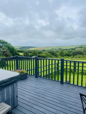 a wooden deck with a view of the rolling hills at The Piggery @ Goonwinnow Farm in Newquay