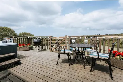 a patio with a table and chairs on a deck at The Piggery @ Goonwinnow Farm in Newquay