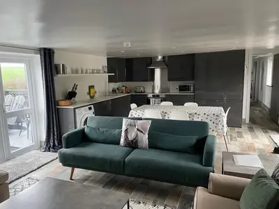 a living room with a green couch and a kitchen at The Piggery @ Goonwinnow Farm in Newquay