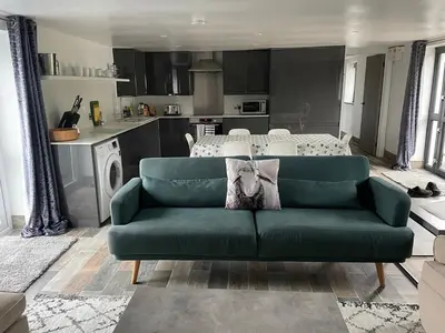a living room with a green couch and a kitchen at The Piggery @ Goonwinnow Farm in Newquay