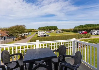 a table and chairs on a balcony with a view of a park at Trevornick Holiday Park in Holywell Bay