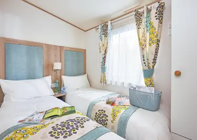 a hotel room with two beds and a window at Trevornick Holiday Park in Holywell Bay