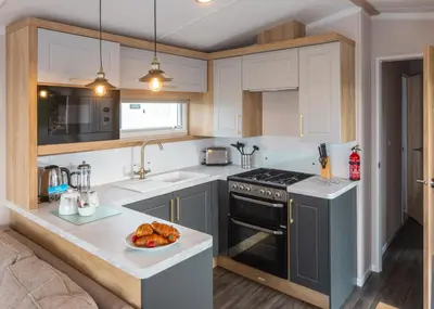 a kitchen with a stove and a plate of food on a counter at Trevornick Holiday Park in Holywell Bay
