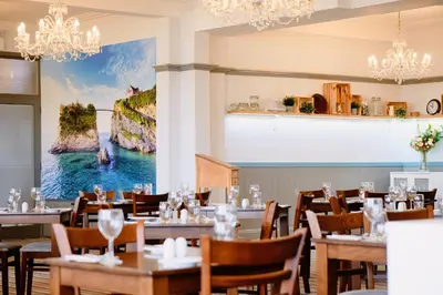 a dining room with tables and chairs and a painting on the wall at The Kilbirnie Hotel in Newquay