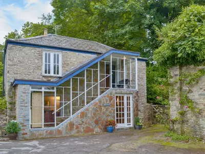 a small stone house with a large window at Granny's Cottage in Lostwithiel