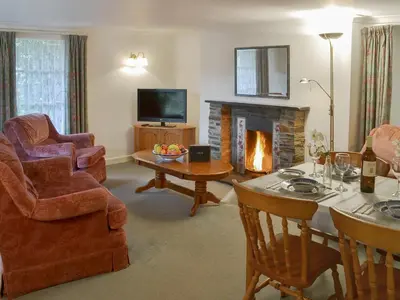 a living room with a fireplace and a table and chairs at Granny's Cottage in Lostwithiel