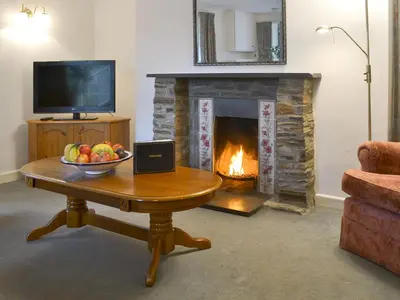 a living room with a fireplace and a table with a bowl of fruit at Granny's Cottage in Lostwithiel