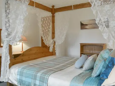 a bedroom with a wooden bed with blue pillows at Granny's Cottage in Lostwithiel