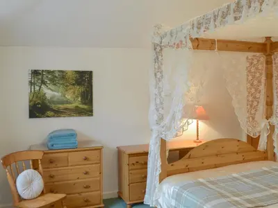 a bedroom with a wooden bed and a dresser at Granny's Cottage in Lostwithiel