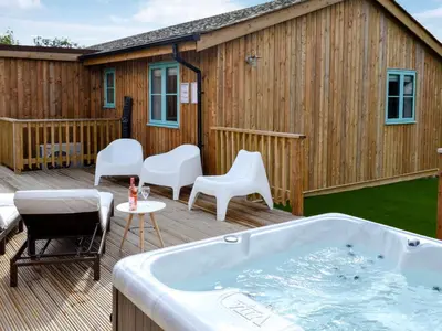 a deck with a hot tub and chairs and a building at Eagle Owl Lodge-Ukc3770 in Saint Columb Major