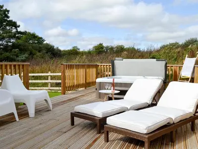 a deck with white furniture and a table and chairs at Eagle Owl Lodge-Ukc3770 in Saint Columb Major