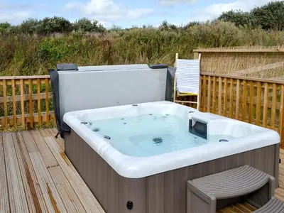 a hot tub on a deck with a chair at Eagle Owl Lodge-Ukc3770 in Saint Columb Major