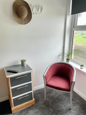 a red chair sitting next to a dresser next to a window at Breakers Guest House in Newquay