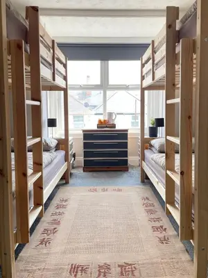a room with three bunk beds with a desk at Breakers Guest House in Newquay