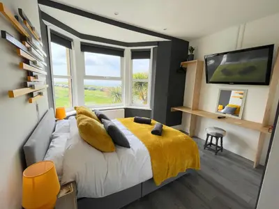 a bedroom with a bed with a yellow blanket and a window at Breakers Guest House in Newquay