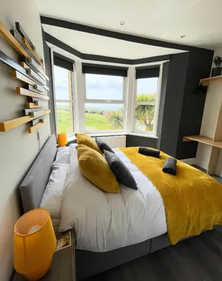 a bedroom with a bed with yellow sheets and a window at Breakers Guest House in Newquay