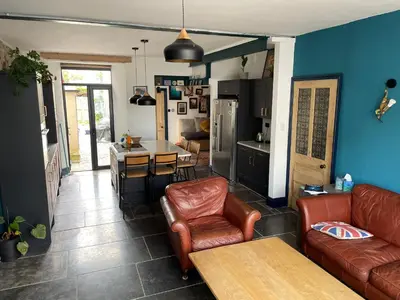 a living room with leather furniture and a kitchen at Fistral Court in Newquay