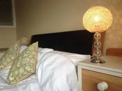 a bed with white sheets and a lamp on a night stand at Fistral Court in Newquay