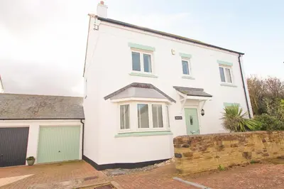a white house with green doors and a garage at MODERN HOLIDAY HOME central St Merryn in St Merryn