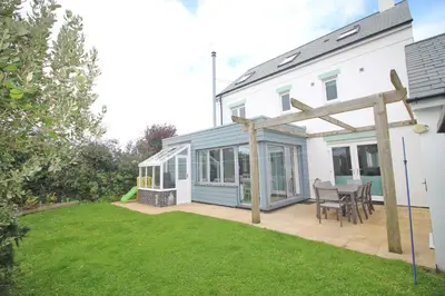 a house with a patio with a table and chairs at MODERN HOLIDAY HOME central St Merryn in St Merryn