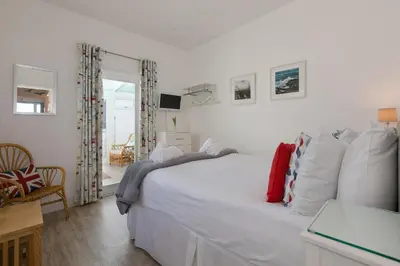 a bedroom with a large white bed and a chair at SeaCrest 1 in St Ives