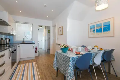 a kitchen and a table with a blue table cloth at SeaCrest 1 in St Ives
