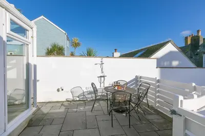 a patio with a table and chairs on a white fence at SeaCrest 1 in St Ives