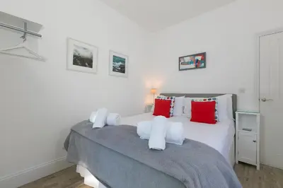 a bedroom with a large white bed with red pillows at SeaCrest 1 in St Ives