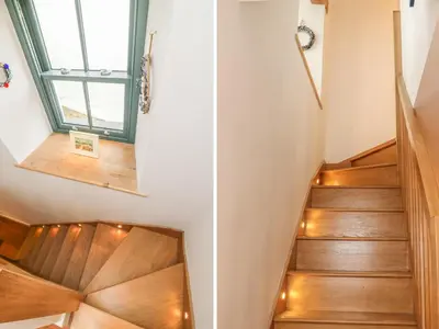a staircase in a house with wooden floors and lights at Lantern Cottage in Padstow