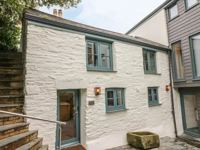a white stone house with blue windows and stairs at Lantern Cottage in Padstow
